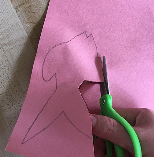 Cutting out the outline of a fish drawn on pink paper