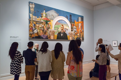 The Andrew W. Mellon Summer Academy participants viewing Edward Biberman's Abbot Kinney and the Story of Venice, lent by the United States Postal Service ®. Recent conservation provided by Joel Silver. Photo © Museum Associates/ LACMA