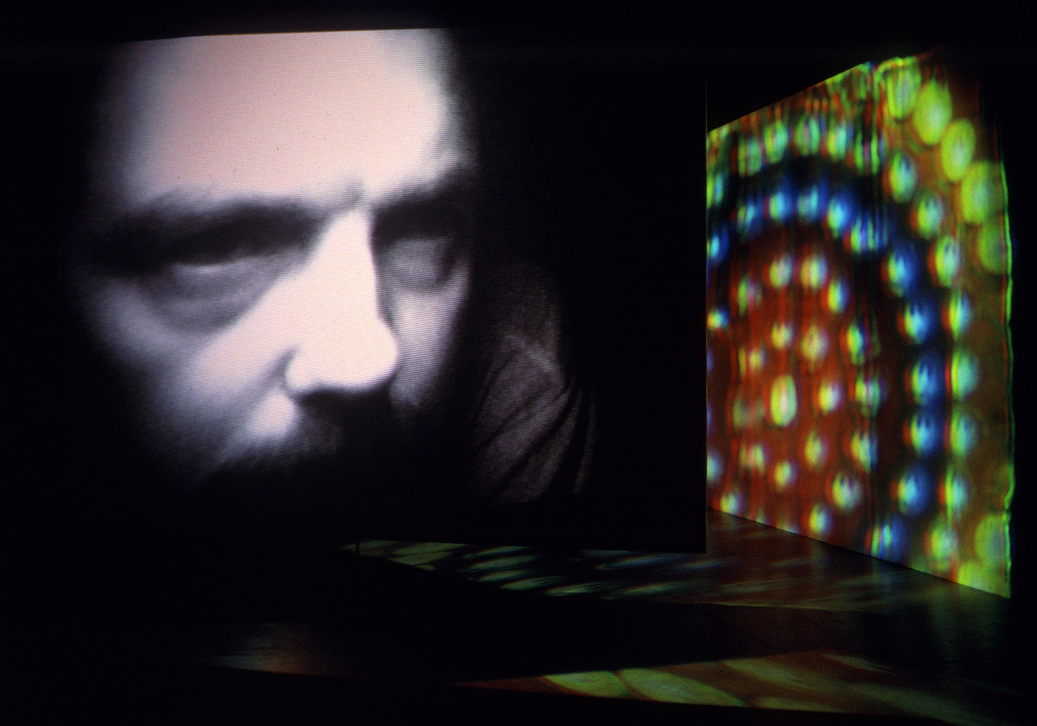 Projection of a man's face and colorful round lights in dark room