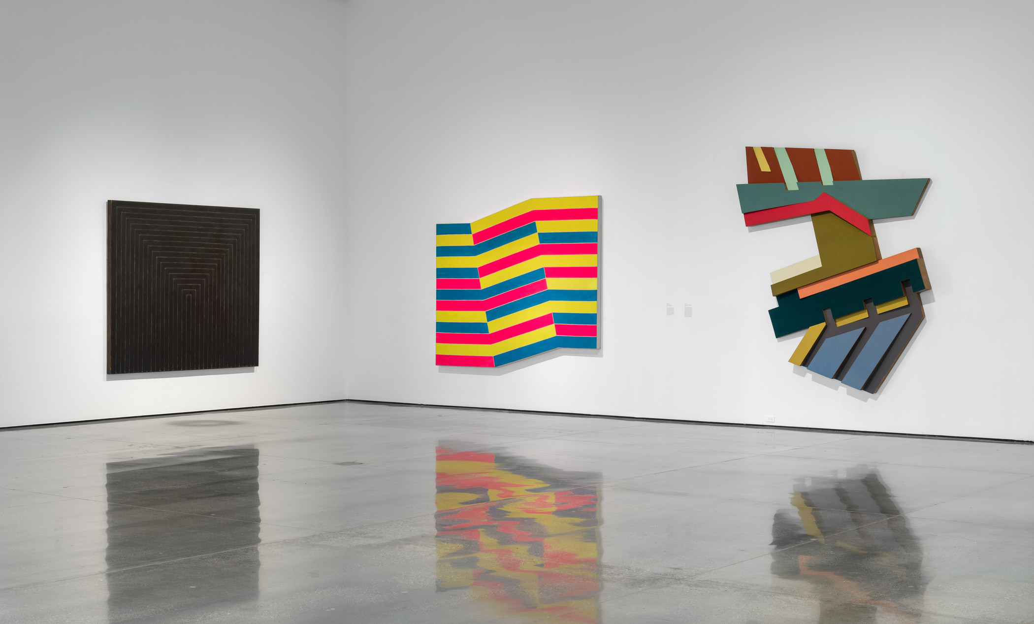 Installation photograph, Frank Stella: Selections from the Permanent Collection, Los Angeles County Museum of Art, May 5–September 15, 2019, art © 2019 Frank Stella/Artists Rights Society (ARS) New York, photo © Museum Associates/LACMA. From left: Getty Tomb, 1959, Contemporary Art Council Fund; Bampur, 1966, gift of the Phil Gersh Agency, Inc. through the Contemporary Art Council; Rozdol II, 1973, gift of The Douglas S. Cramer Foundation