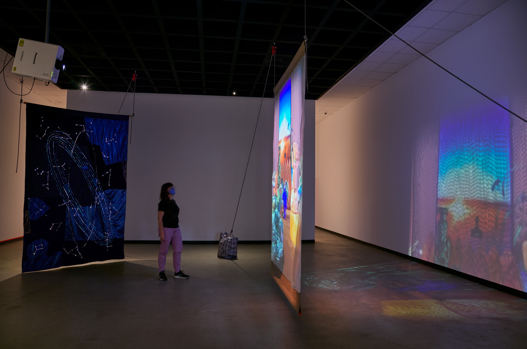 Photograph of a person viewing a video projection, with a large banner behind the person