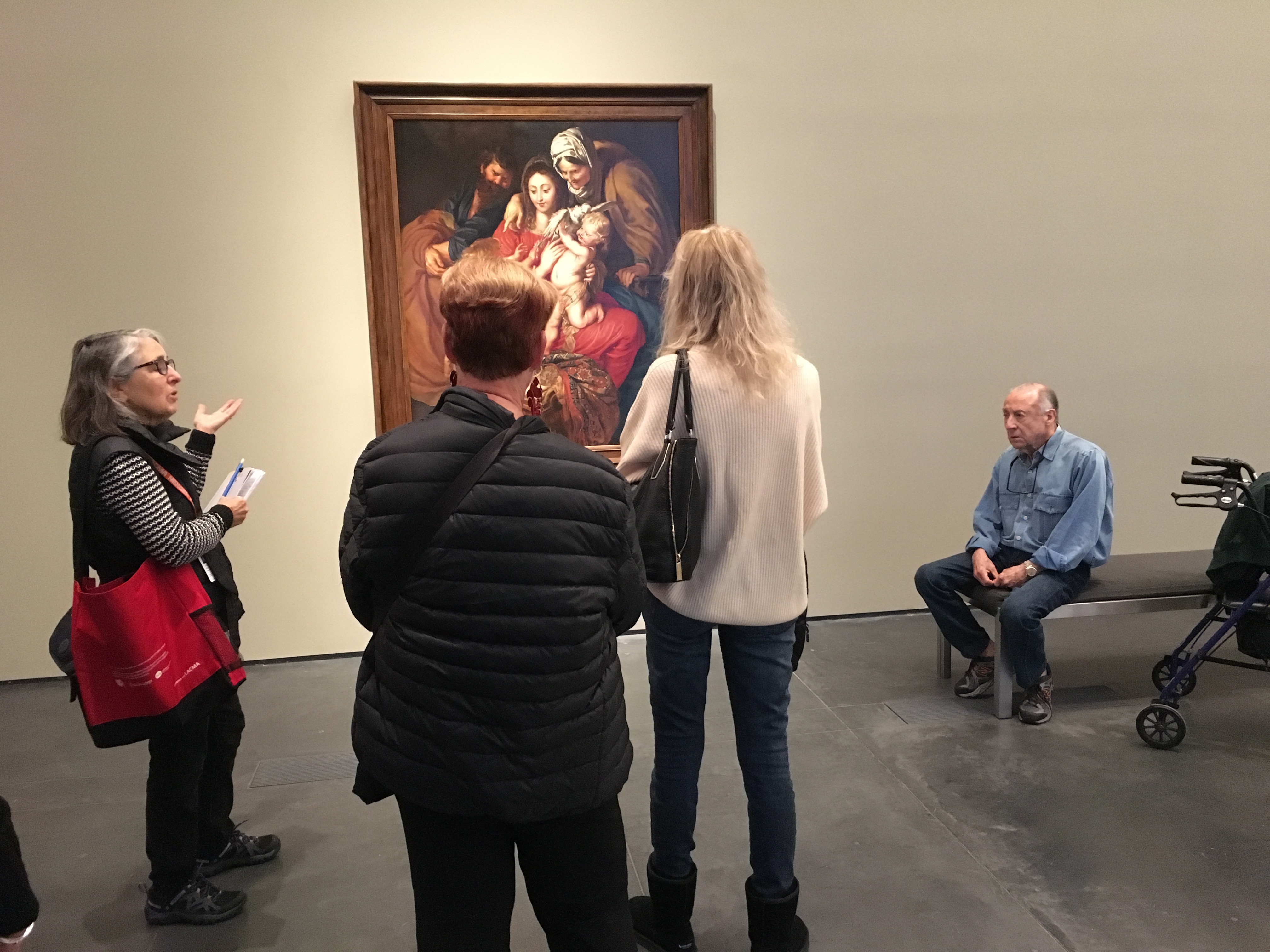 Tour participants engage in conversation around Peter Paul Rubens's The Holy Family with St. Elizabeth, St. John, and a Dove in To Rome and Back: Individualism and Authority in Art, 1500–1800.