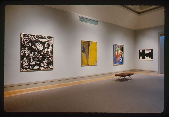Photograph of gallery with four paintings on the wall
