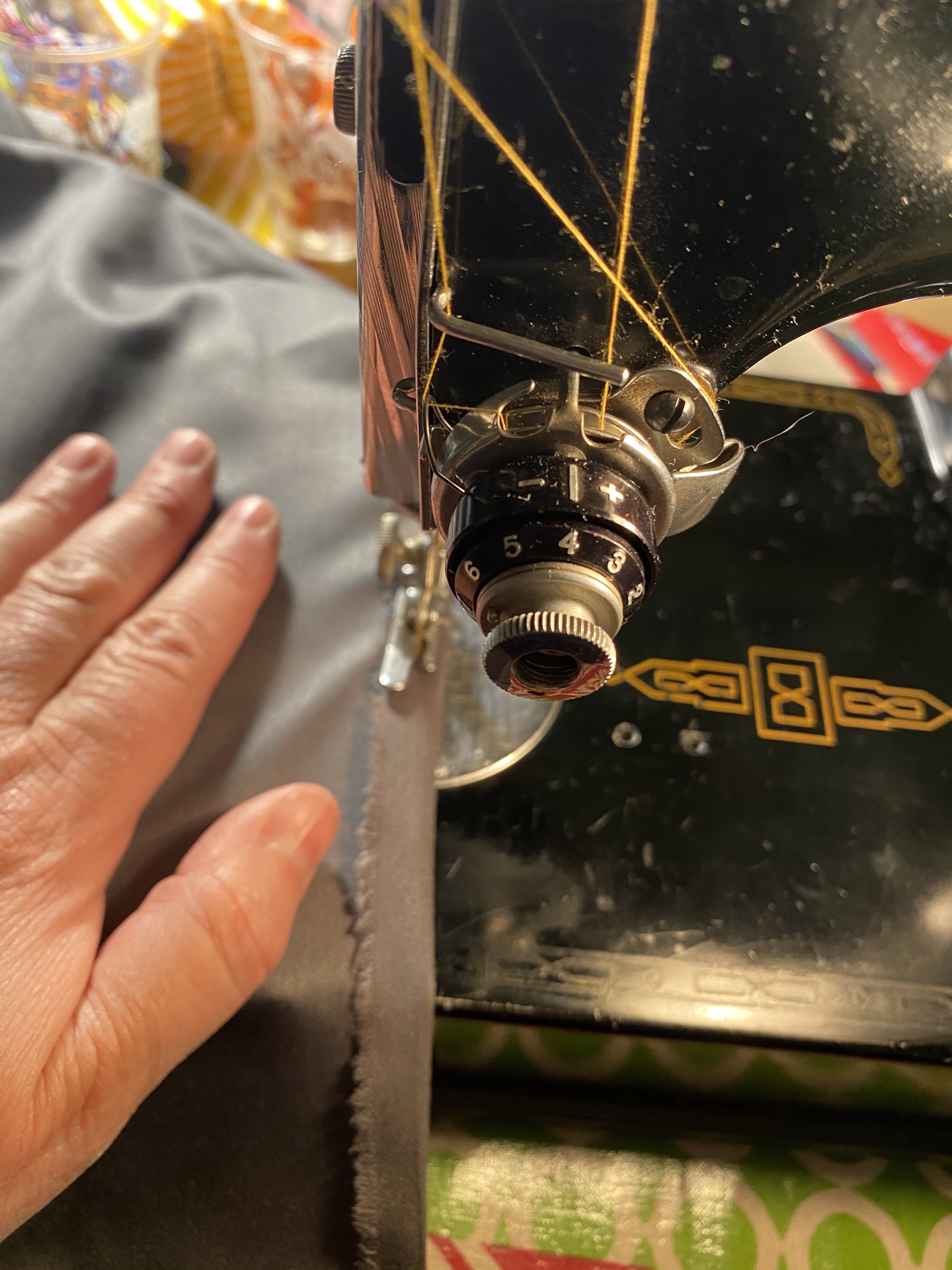 Close-up of a hand moving fabric through a black sewing machine