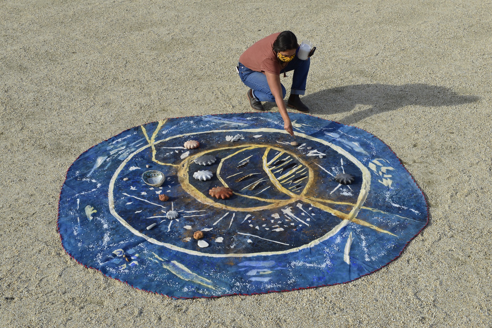 Woman working on a round canvas on gravel