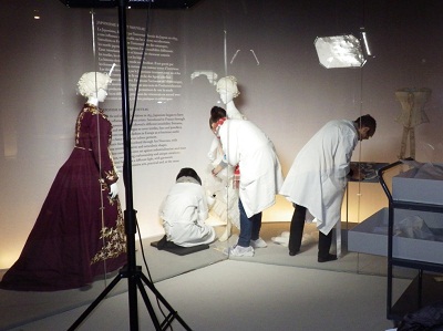 LACMA and Les Arts Décoratifs staff installs a vitrine that displays late 19th century garments