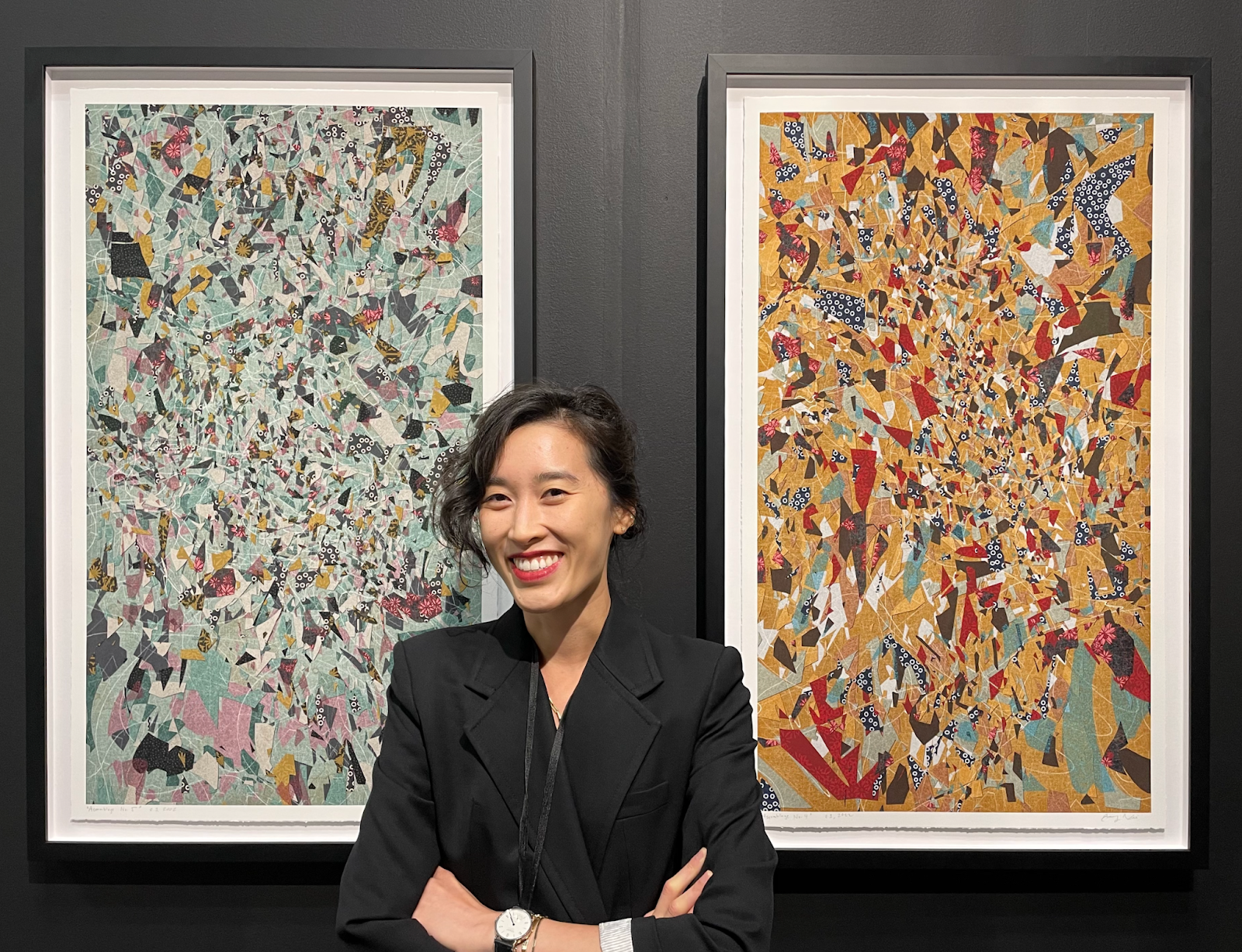 Emily Xie smiling with arms crossed between two framed prints of dense, colorful collage fragments