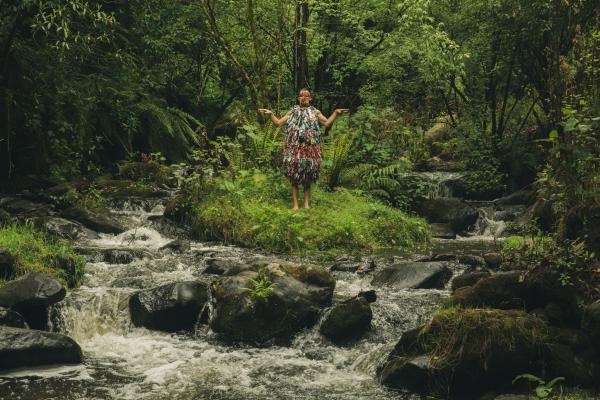 Figure in colorful costume standing next to a woodland stream