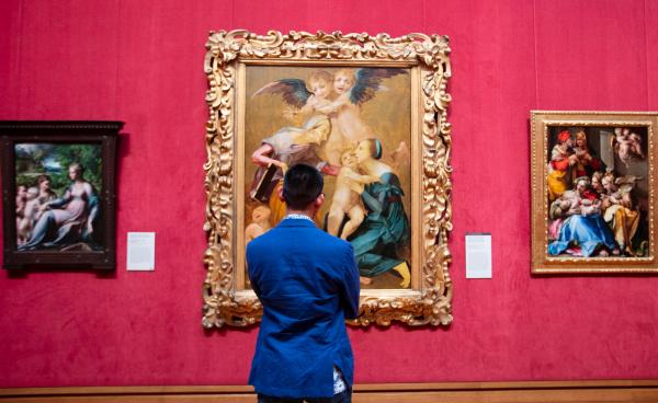 A visitor stands in front of European paintings hanging in the Getty, including Allegory of Salvation