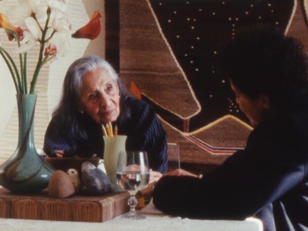 Film still of two women sitting down and talking
