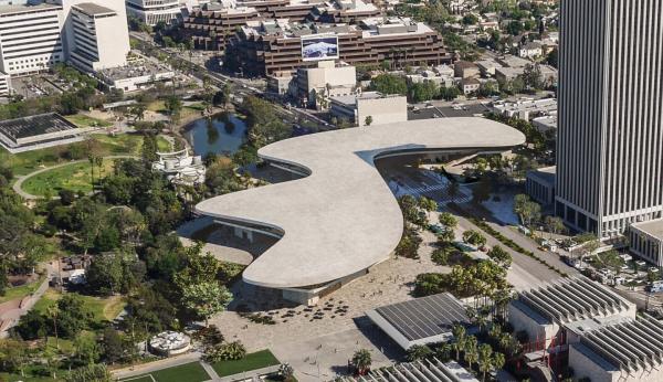 Overhead view of organically shaped gray building surrounded by vegetation and buildings