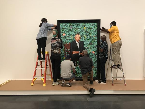 People installing a portrait of Barack Obama by Kehinde Wiley