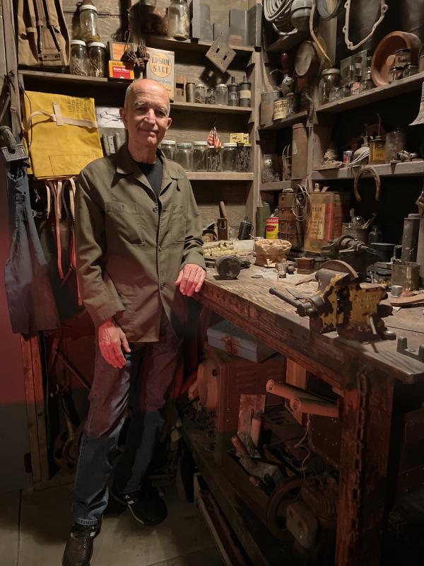 Michael C. McMillen standing at a darkened work table in his installation “Central Meridian”