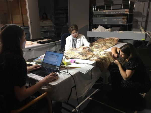 Costume and Textiles staff at work: Sharon Takeda (center) is verbally cataloging the kimono while Jennifer Iacovelli (left) enters the information into the database, and Michaela Hansen (right) is assessing the weave structure.