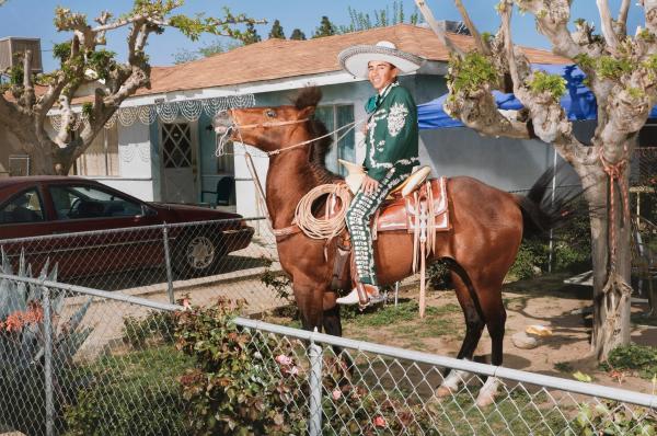 Man riding horse in front of a house