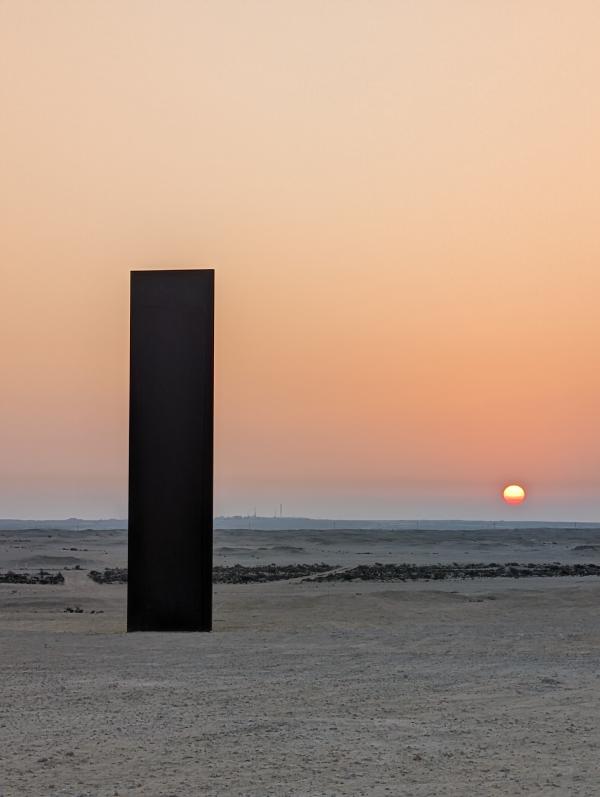 Photograph of a steel plinth on a beach at sunset