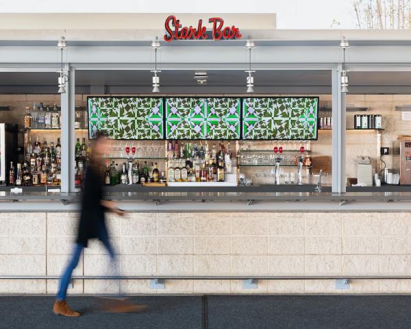 Figure walking by video screens behind a restaurant bar