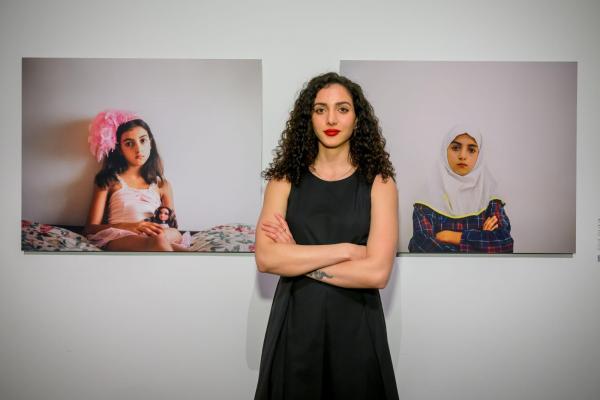 Woman standing in front of two wall-mounted photos of a girl
