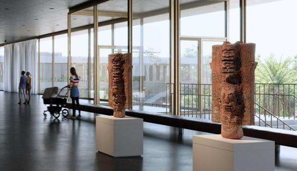 Interior of gallery with floor-to-ceiling windows showing visitors and art