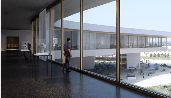 Person in gallery looking out floor-to-ceiling windows with curving building in sight