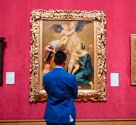 A visitor stands in front of European paintings hanging in the Getty, including Allegory of Salvation