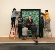 People installing a portrait of Barack Obama by Kehinde Wiley