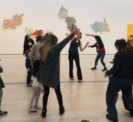 People dancing in front of Robert Rauschenberg's The 1/4 Mile or 2 Furlong Piece