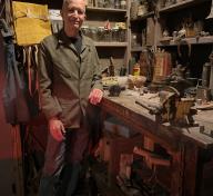 Michael C. McMillen standing at a darkened work table in his installation “Central Meridian”