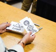 Hands holding cards with marker drawings