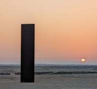 Photograph of a steel plinth on a beach at sunset