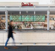 Figure walking by video screens behind a restaurant bar