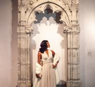 Woman in gown standing in front of stone arch
