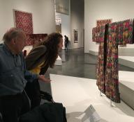 Artist Educator Elonda Norris carefully examines a textile in Power of Pattern: Central Asian Ikats from the David and Elizabeth Reisbord Collection with a Personal Connections participant.