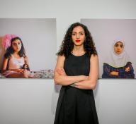 Woman standing in front of two wall-mounted photos of a girl