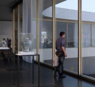 An adult and child look out floor-to-ceiling windows of museum gallery with art