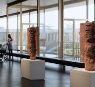 Interior of gallery with floor-to-ceiling windows showing visitors and art