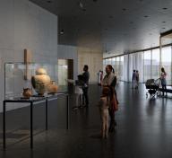 Visitors in art gallery with floor to ceiling windows on the right side of the image