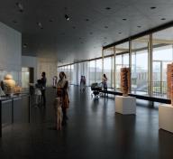 Rendering of gallery with floor to ceiling glass and ancient American art with visitors