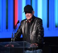 Man in black ball cap and leather jacket at podium