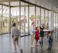 Rendering of gallery with floor-to-ceiling windows, people, and art