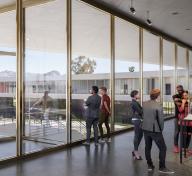 Rendering of gallery interior with floor to ceiling glass walls and visitors viewing art