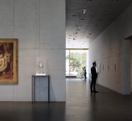 Interior view of gallery with a figure looking at art on walls