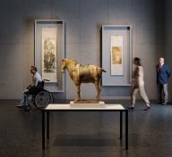 Sculpture of horse in the middle of a dark art gallery with visitors