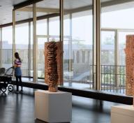 Two sculptures displayed in light-filled gallery with person with stroller