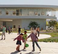 Rendering of children playing with a ball in front of a tall light gray building